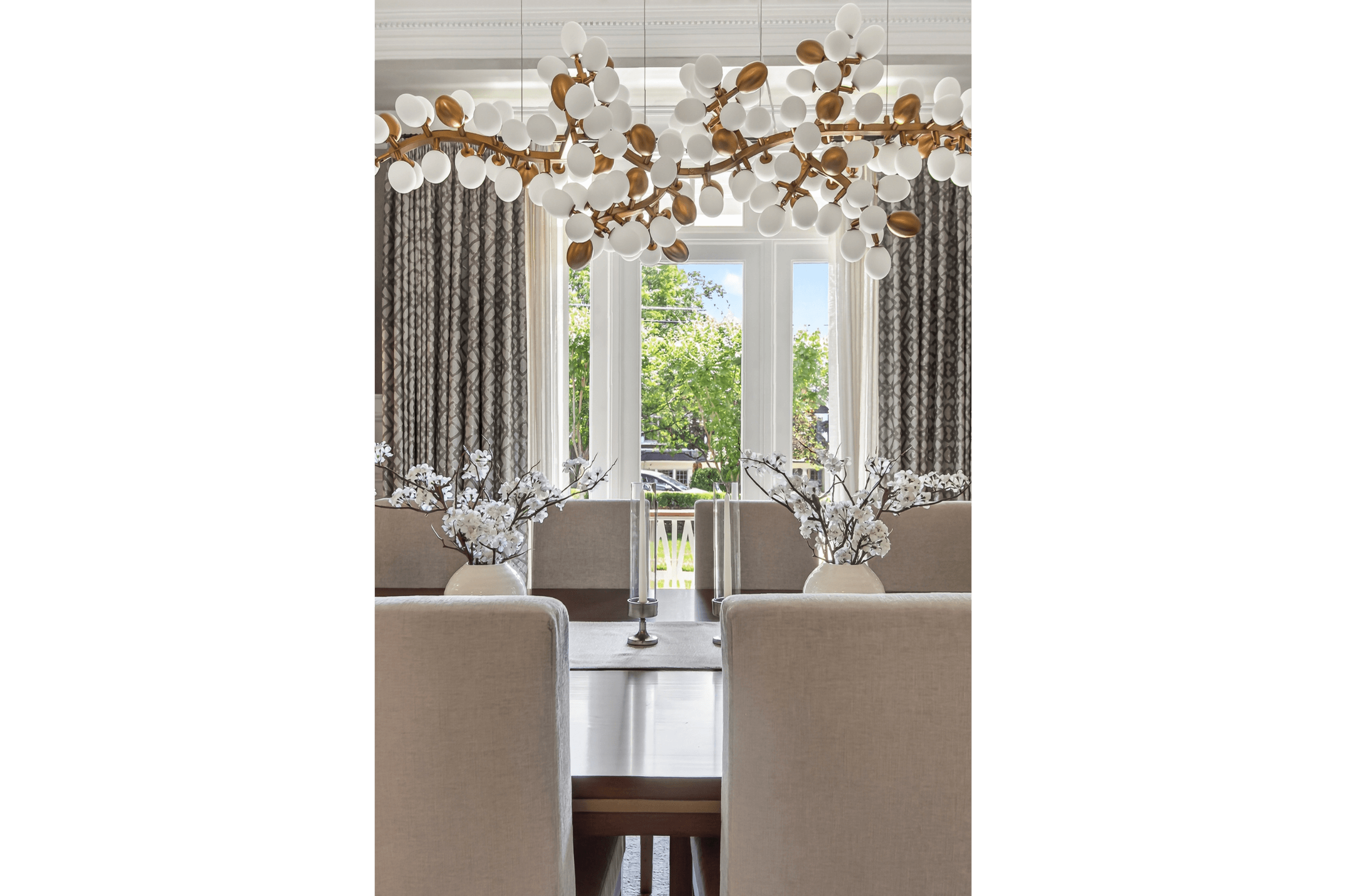 Luxury interior dining room with statement branch lighting and elegant white cherry blossom centerpieces.