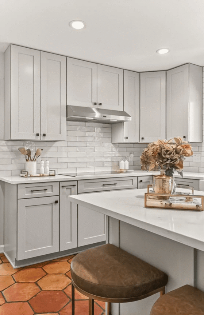 Modern kitchen featuring gray cabinetry, white subway tile, a marble countertop, and stylish decor elements.